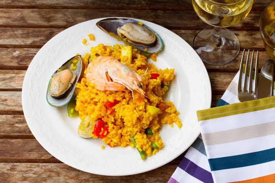 Paella served in white plate on wooden table