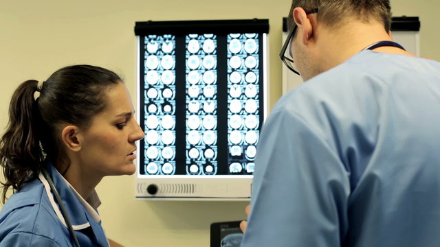 Doctors with tablet computer looking at x-ray scan of brain