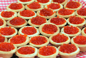 Tartlets with red caviar on a checkered plate