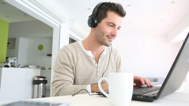 Man in font of laptop with headset on