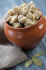Boiled pelmeni or meat dumplings in a pot on a wooden table