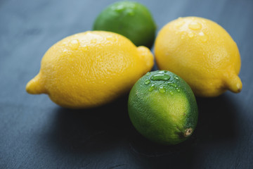 Limes and lemons on a black wooden surface, horizontal shot