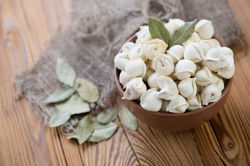 Raw pelmeni or meat dumplings with bay leaves, horizontal shot