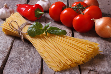 Spaghetti, tomatoes and basil on old table closeup