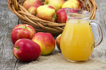 Apple juice and apples on wooden background