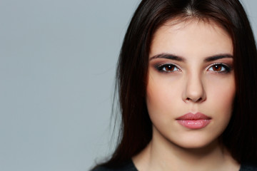 Naklejka premium Closeup portrait of a young mysterious woman on gray background