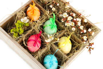 Naklejka premium Easter eggs in wooden box with hay isolated on white