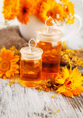 Medicine bottles and calendula flowers on wooden background