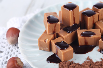 Many toffee on plate on napkin on wooden table