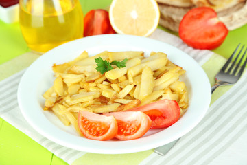 Ruddy fried potatoes on plate on wooden table close-up