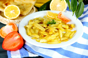 Ruddy fried potatoes on plate on tablecloth close-up