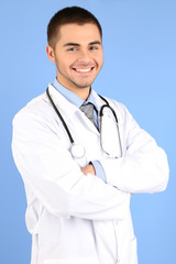 Male Doctor standing with folder, on blue background