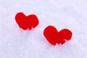 Little felt hearts on snowy background