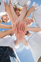 Happy volunteers with hands together against blue sky