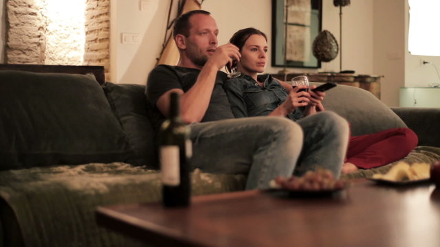 Young couple sitting on sofa and watching tv