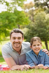 Fototapeta premium Father with young daughter lying on grass in park
