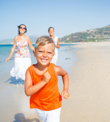 Cute boy with sister and mother on the beach