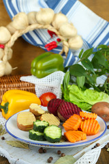 Beautiful sliced vegetables, on plate, on wooden background