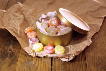 Fototapeta na wymiar Sweet candies in metal can, on wooden background
