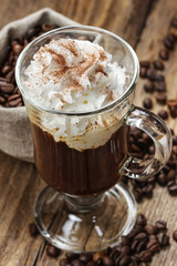 Irish coffee on wooden table among coffee beans