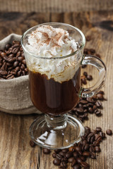 Irish coffee on wooden table among coffee beans