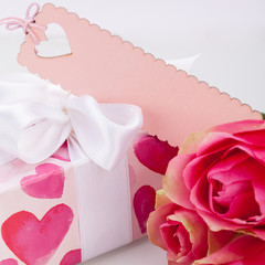kleines verpacktes geschenk mit herzen und rosen in pink