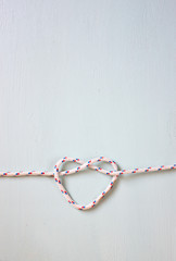 Heart Shaped Knot on a rope on blue wooden textured background  