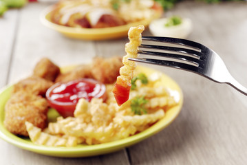 French fries and chicken on the plate on the wooden table