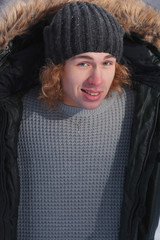 Young man holds his jacket in winter Park