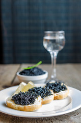 Sandwiches with black caviar and glass of vodka