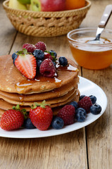 Pancakes with berries and honey closeup