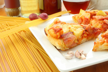 Some pizza on white plate in kitchen.
