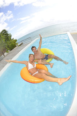 Cheerful couple having fun in swimming-pool