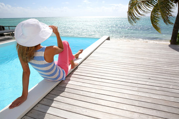 Rear view of fashion girl sitting by infinity pool