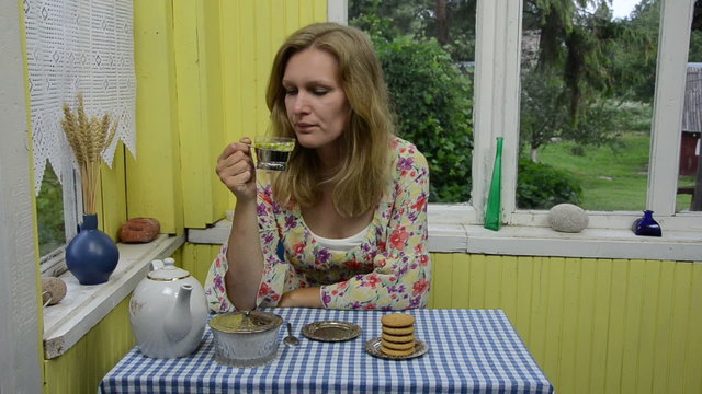 Woman drink herbal camomile tea in rural homestead veranda