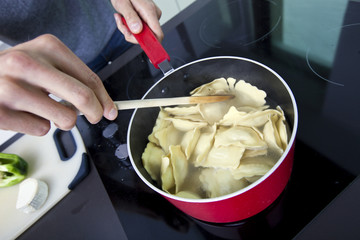 Midsection of man cooking pasta on stove in kitchen