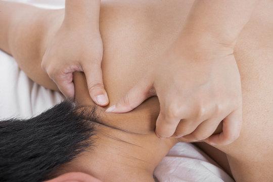 Cropped image of woman massaging man's shoulder in bed