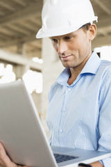 Confident male architect using laptop at construction site