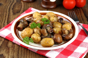 Brown champignons with rosemary potato on wood background
