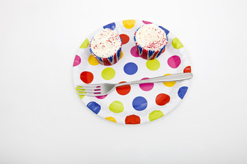 High angle view of cupcakes in multicolored plate against white background