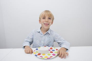 Portrait of happy boy with cake slice in plate on table at home