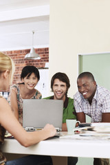 Fototapeta premium Four people having meeting around laptop laughing.