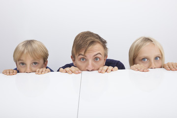 Father and children peeking over table