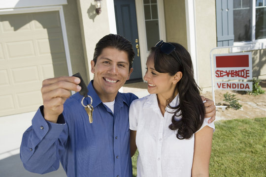 Young couple holding keys outside new home portrait