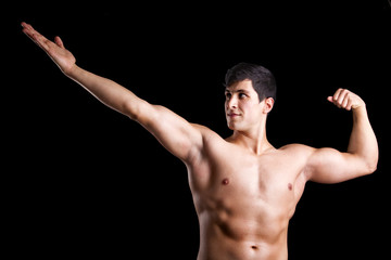 Fototapeta na wymiar Muscle young man posing against a dark background