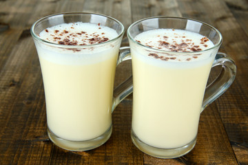 Cups of eggnog on wooden background