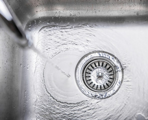 Water flowing down the hole in a kitchen sink - 59832874