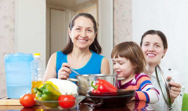 Happy women  with child  cooking veggie lunch