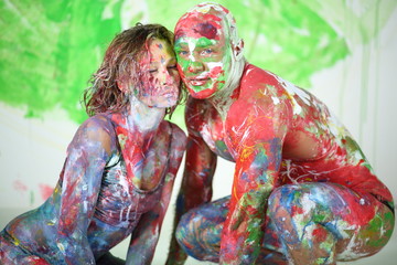 Man and girl sitting in studio with whole body in paint