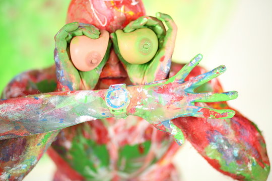 A man covered in paint held to eyes toy tits and female hand